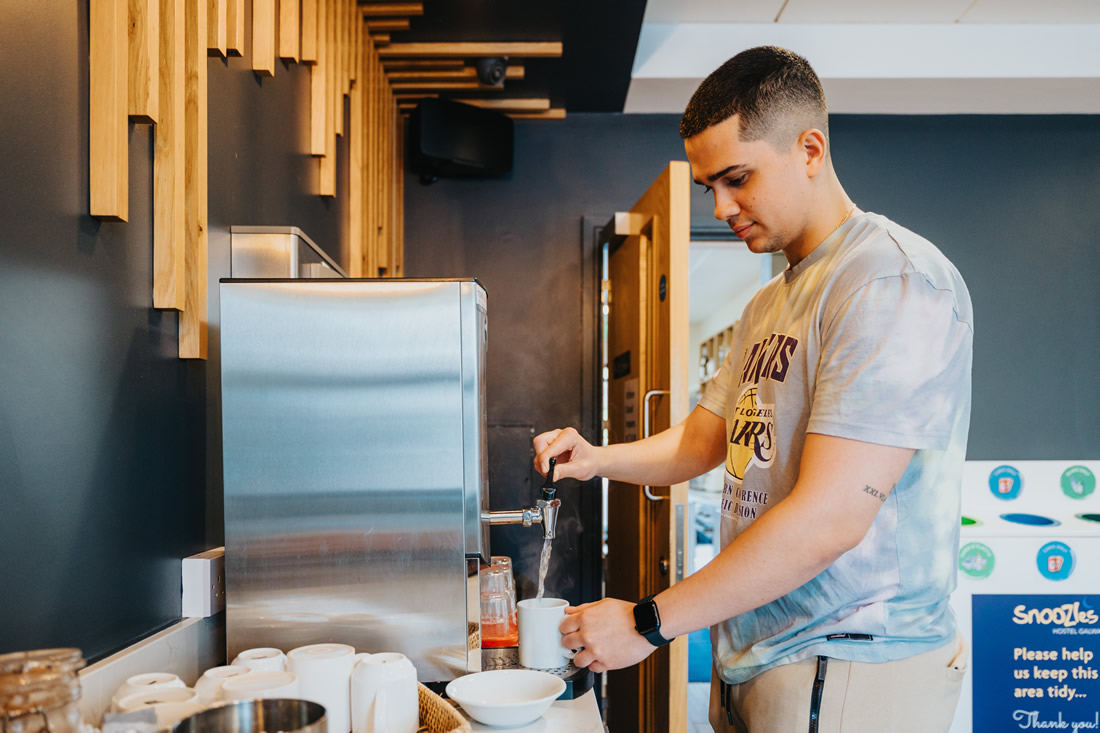 Guest making a hot drink in the hostel’s shared kitchen area